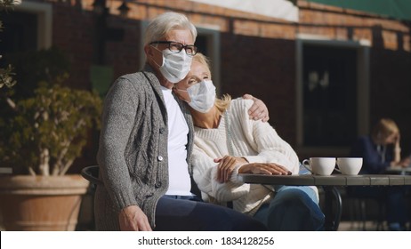 Mature Couple In Protective Mask Hugging Sitting In Street Cafe