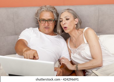 Mature Couple Relaxing In Bed Reading And Chatting