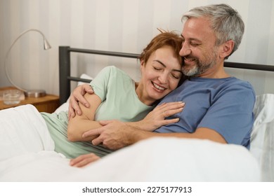 Mature couple relaxing and cuddling in bed in the morning at home - Powered by Shutterstock