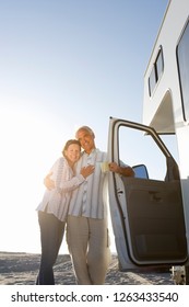 Mature Couple Relaxing On Motor Home Vacation At Beach At Camera