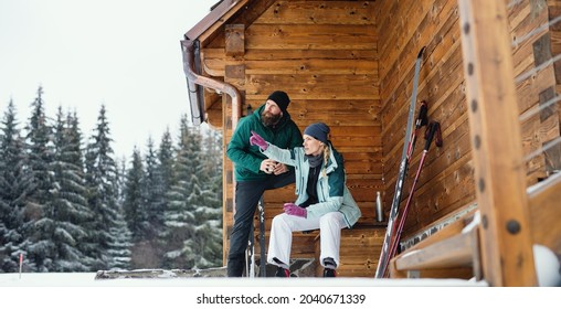 Mature couple resting by wooden hut outdoors in winter nature, cross country skiing. - Powered by Shutterstock