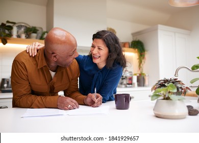 Mature Couple Reviewing And Signing Domestic Finances And Investment Paperwork In Kitchen At Home - Powered by Shutterstock