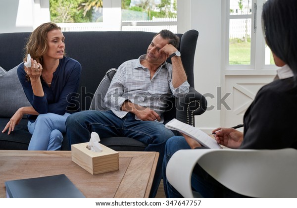 mature couple seated on couch, woman crying\
during therapy session