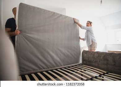 Mature Couple Are Setting Up Their Bed In Their New Home. 