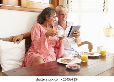 Mature Couple Sitting At Breakfast Table With Digital Tablet - Powered by Shutterstock