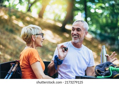 Mature couple sitting and drink coffee while resting in the forest. - Powered by Shutterstock