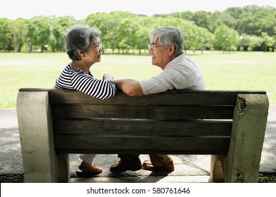 Mature Couple Sitting Face To Face On Park Bench