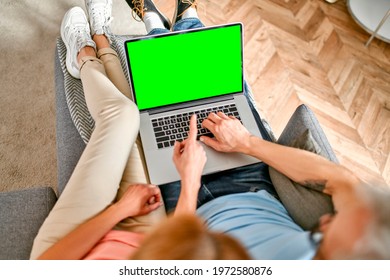 Mature couple is sitting on the couch at home with a laptop. Green screen, blank space for insertion. Online shopping. - Powered by Shutterstock