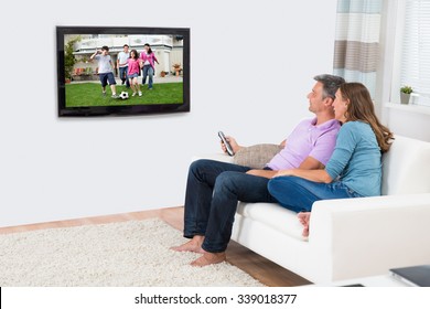 Mature Couple Sitting On Sofa And Enjoying Watching Television