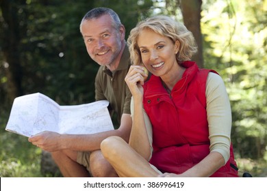A mature couple sitting outdoors resting, man holding a map