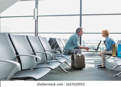 Mature Couple Sitting While Waiting For Their Flight In Airport