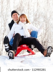 Mature Couple Sledding. Seniors Couple On Sled In Winter Park