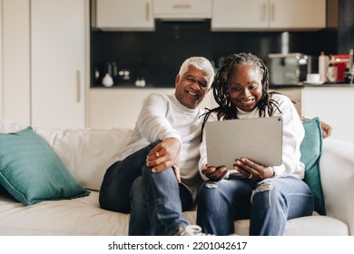 Mature couple smiling happily while having a video call on a digital tablet. Cheerful senior couple communicating with their loved ones online. Mature couple enjoying their retirement at home. - Powered by Shutterstock