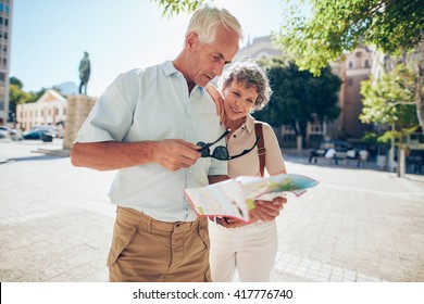 Mature couple standing outdoors in the city looking at a map. Senior man with his wife using city map for finding their location. - Powered by Shutterstock