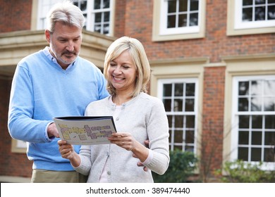 Mature Couple Standing Outside House Looking At Property Details