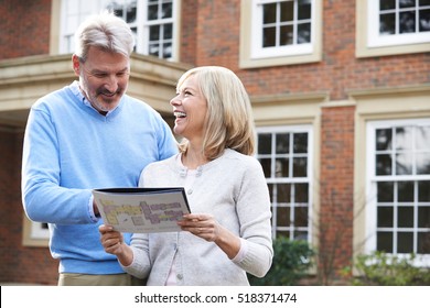 Mature Couple Standing Outside House Looking At Property Details