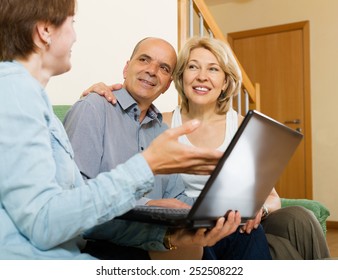 Mature Couple Talking With Employee With Laptop At Home