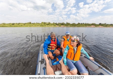 mature couple tourists travel on an inflatable boat with a motor on the Volga river on a summer day