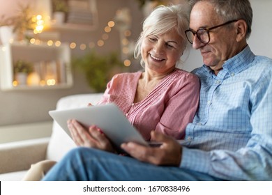 Mature couple using a laptop while relaxing at home - Powered by Shutterstock