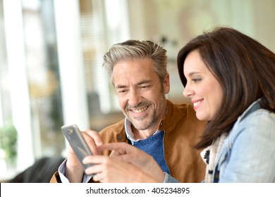 Mature Couple Using Smartphone In Coffee Shop