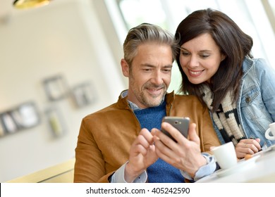 Mature Couple Using Smartphone In Coffee Shop