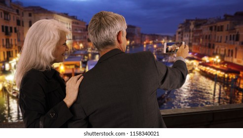 Mature Couple In Venice Looking At Picture On Their Smartphone