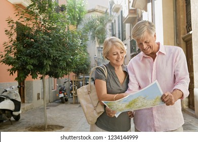 Mature Couple Visiting Picturesque City Street On Holiday, Reading Map Sightseeing, Joyful Smiling, Sunny Outdoors. Senior People Travel Leisure Recreation Lifestyle, Retirement Activities.