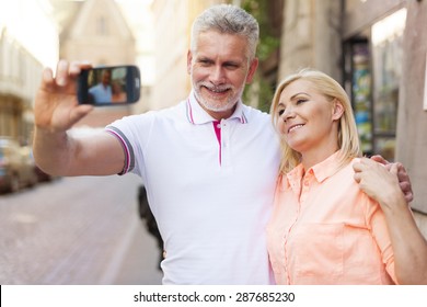 Mature Couple Walking In City And Taking Selfie By Mobile Phone 