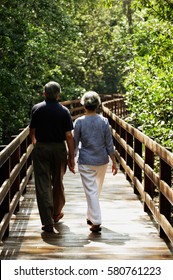 Mature Couple Walking On Wooden Bridge, Rear View