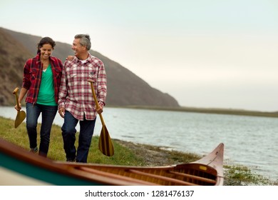 Mature Couple Walking Towards Their Canoe.