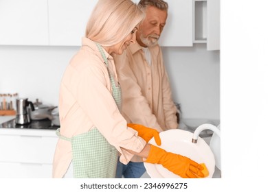 Mature couple washing dishes in kitchen - Powered by Shutterstock