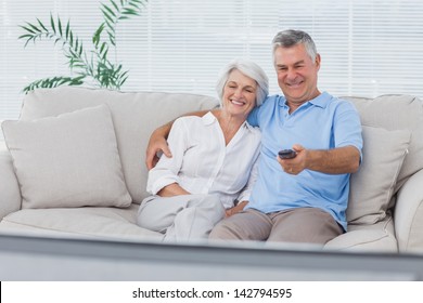 Mature Couple Watching Television Sitting On The Couch