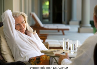 Mature couple wearing bath robes relaxing in chairs at hotel spa