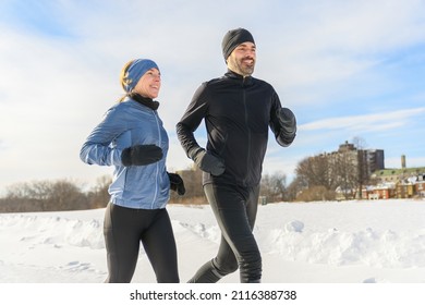 A mature couple in the winter running together in nature