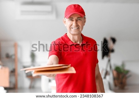 Mature courier with envelopes indoors