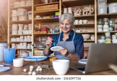 Mature craftswoman painting a plate made of clay in art studio
 - Powered by Shutterstock