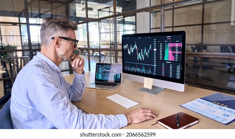 Mature crypto trader investor analyst broker using pc computer analyzing digital cryptocurrency exchange stock market trading graphs report thinking of investing funds risks doing global analysis.