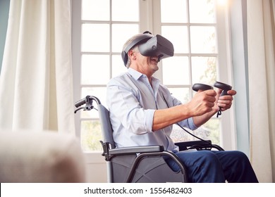 Mature Disabled Man In Wheelchair At Home Wearing Virtual Reality Headset Holding Gaming Controllers - Powered by Shutterstock