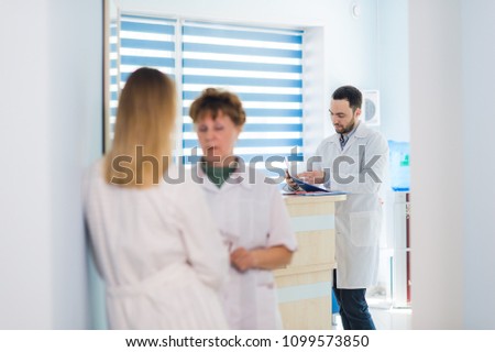 Mature doctor discussing with nurse in a hallway hospital. Doctor discussing patient case status with his medical staff after operation.