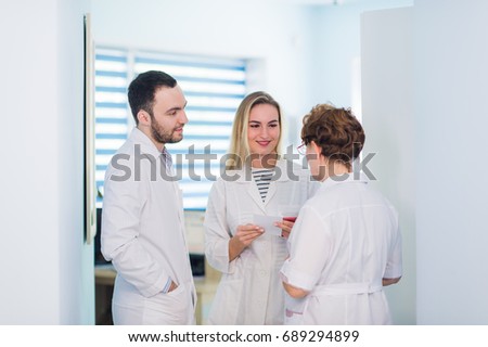 Mature doctor discussing with nurses in a hallway hospital. Doctor discussing patient case status with his medical staff after operation.