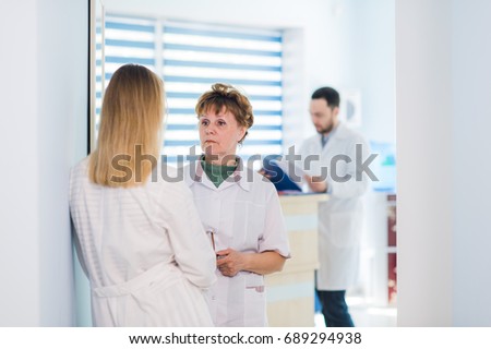 Mature doctor discussing with nurses in a hallway hospital. Doctor discussing patient case status with his medical staff after operation.