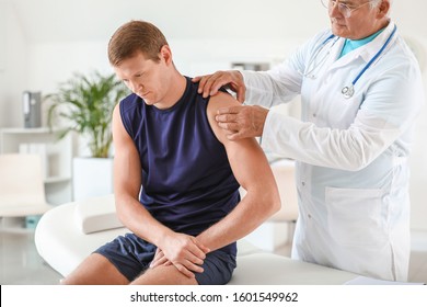 Mature Doctor Examining Sportsman With Joint Pain In Clinic