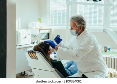 Mature Doctor Giving Female Patient Botox Injection In Forehead. 

Anti Aging Treatment: An anonymous young woman receiving botulinum toxin injection at medical clinic. - Powered by Shutterstock