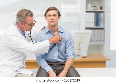 Mature Doctor Listening To His Patients Chest With Stethoscope In His Office At The Hospital