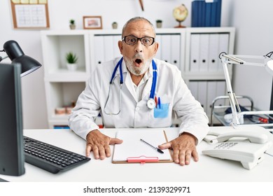 Mature Doctor Man At The Clinic Afraid And Shocked With Surprise Expression, Fear And Excited Face. 