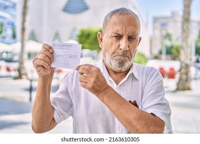 Mature Doctor Man Holding Covid Record Card Skeptic And Nervous, Frowning Upset Because Of Problem. Negative Person. 