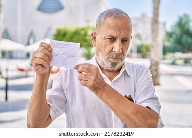 Mature Doctor Man Holding Covid Record Card Skeptic And Nervous, Frowning Upset Because Of Problem. Negative Person. 