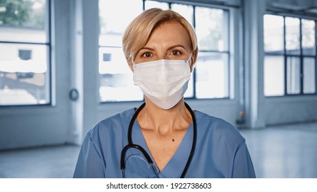 Mature Doctor In Medical Mask Looking At Camera In Hospital