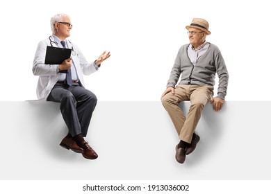 Mature Doctor Sitting On A Blank Panel And Talking To An Elderly Male Patient Isolated On White Background