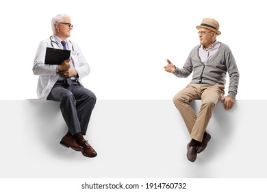 Mature Doctor Sitting On A Blank Panel And Talking With An Elderly Man Isolated On White Background